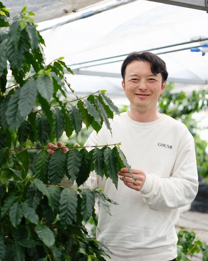 宮崎のハウスでコーヒーの木を手にする代表・山本